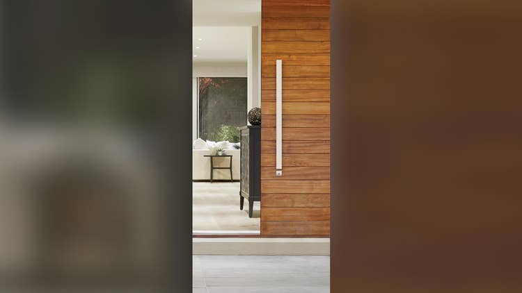 Wooden sliding door with long vertical handle in a modern interior.